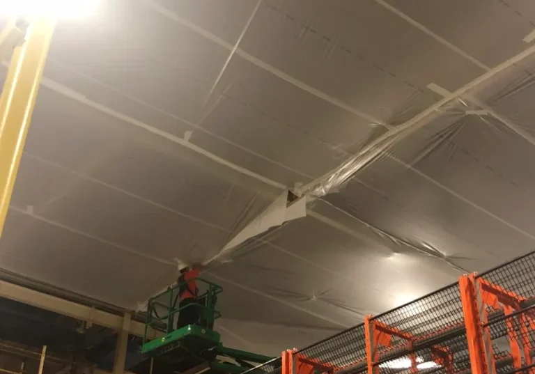 A man on a scissor lift in an industrial setting.